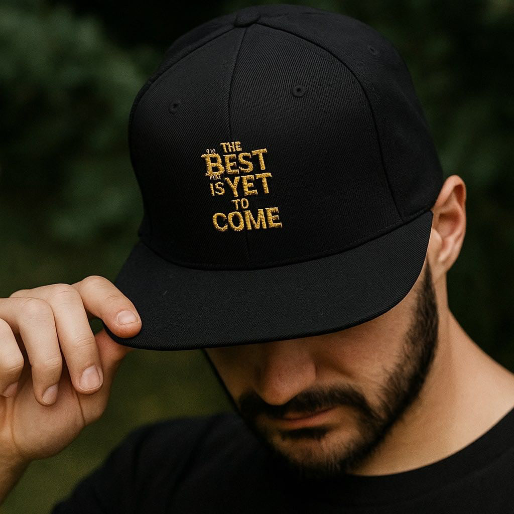 Person wearing a black cap with gold text against a dark background