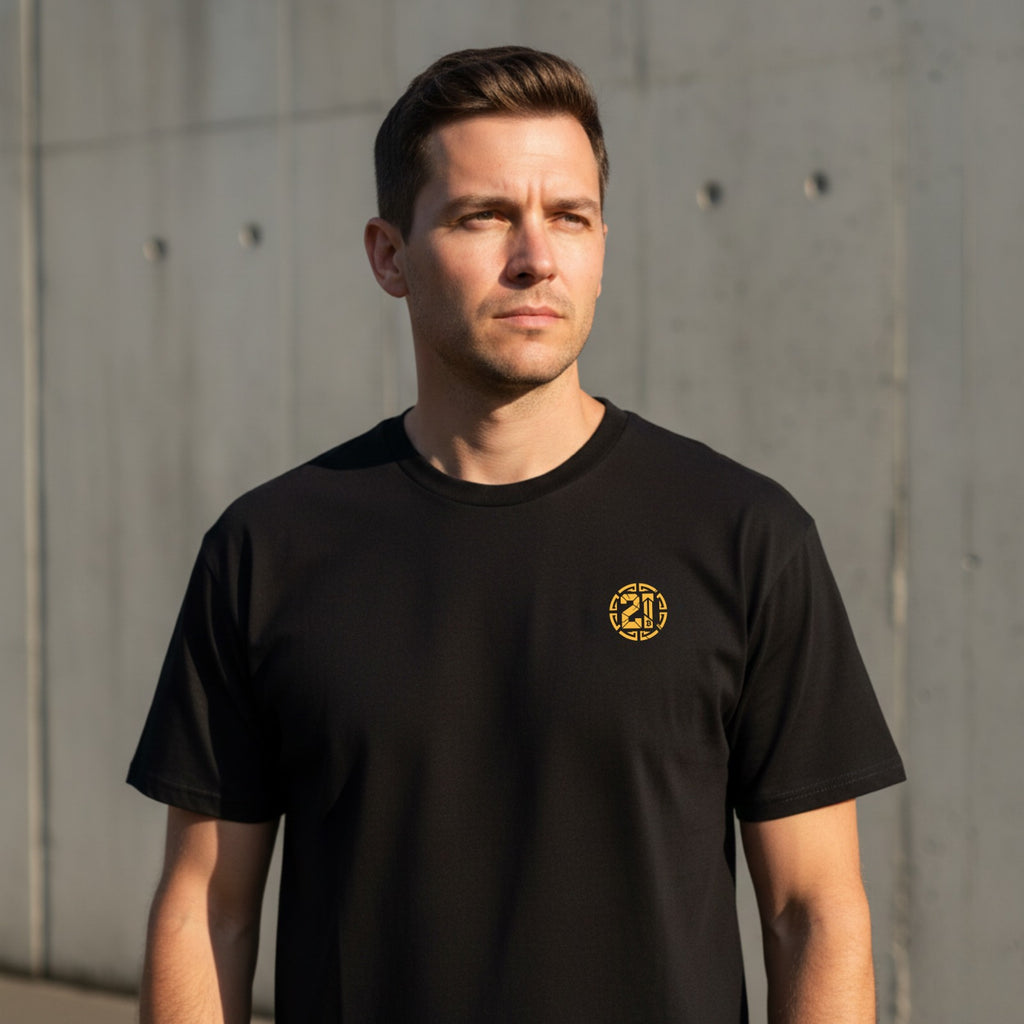 Man wearing a black t-shirt with a logo against a concrete wall.