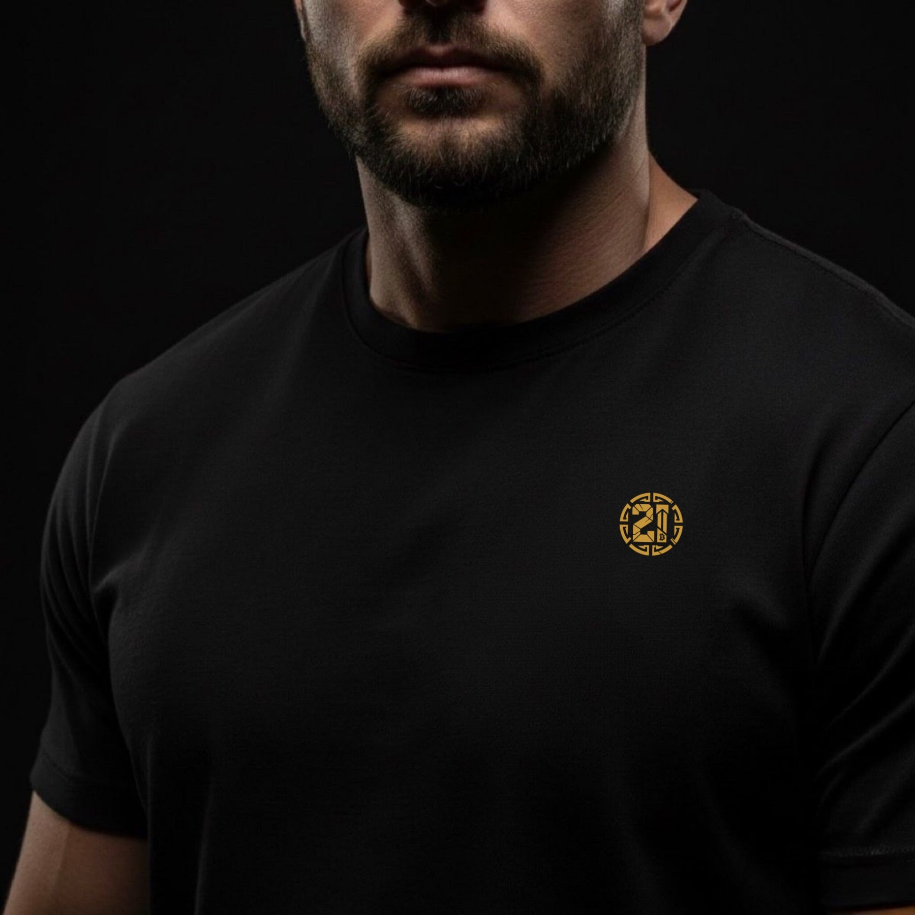 Man wearing a black t-shirt with a gold logo on a black background